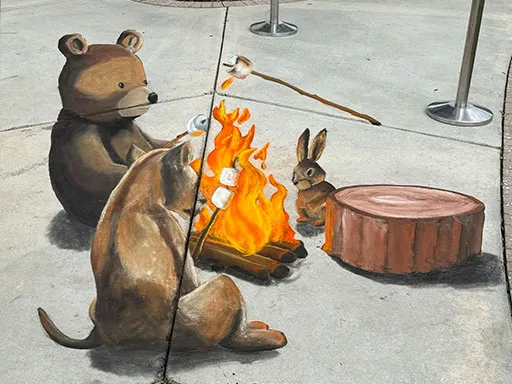 3D chalk art of forest animals toasting marshmallows around a fire.