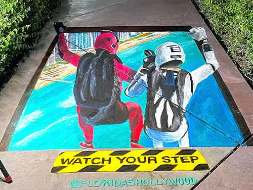 3D chalk art of skydivers over Hollywood Beach