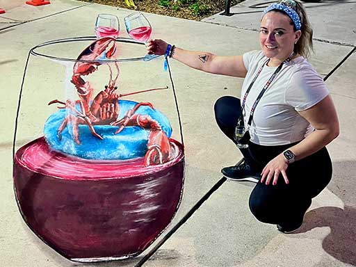 Posing with 3D chalk art of lobster floating on pool floatie inside a wine glass