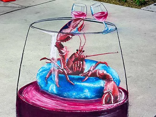 3D chalk art of lobster floating on pool floatie inside a wine glass