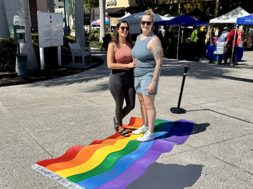 Posing with 3D chalk and painted art of flying carpet Pride flag for Pride month.