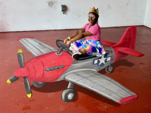 Posing with 3D chalk art of miniature airplane, in the style of the Tuskegee Airmen.