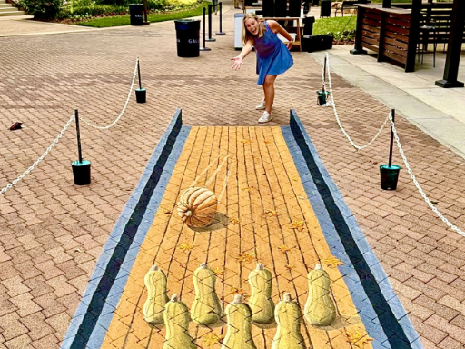 Posing with 3D painted art of pumpkin bowling with butternut squash pins.