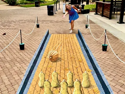 Posing with 3D painted art of pumpkin bowling with butternut squash pins.