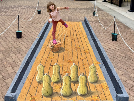 Posing with 3D painted art of pumpkin bowling with butternut squash pins.