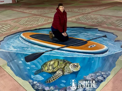 Posing with 3D painted art of paddleboard with sea turtle for Jupiter Jubilee.