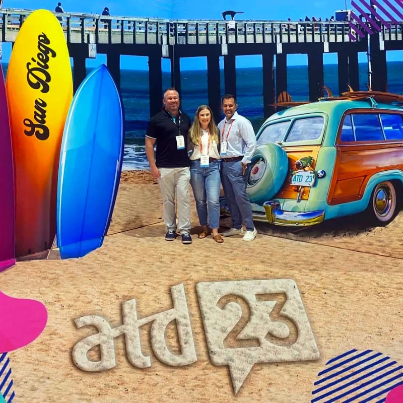 Posing with 3D chalk art convention center photo backdrop of San Diego beach, surfboard, woody car, and pier.